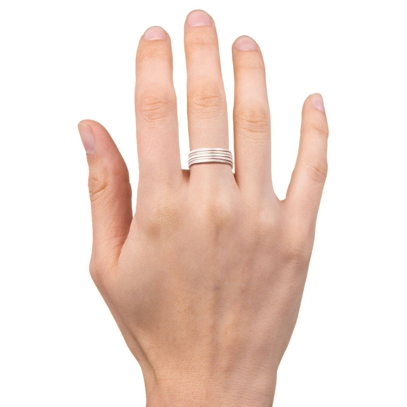 Hand with five stackable silver dime coin rings on the middle finger.