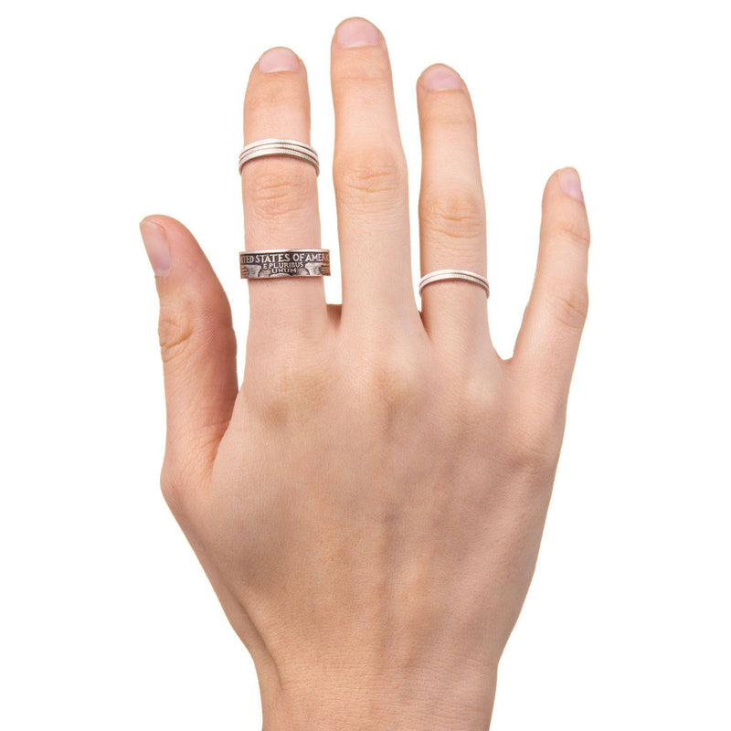Hand showing a combination of stackable silver dime coin rings and a silver quarter ring.