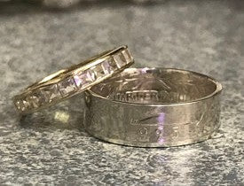 Photo of a silver quarter coin ring and women's wedding ring on a granite countertop.